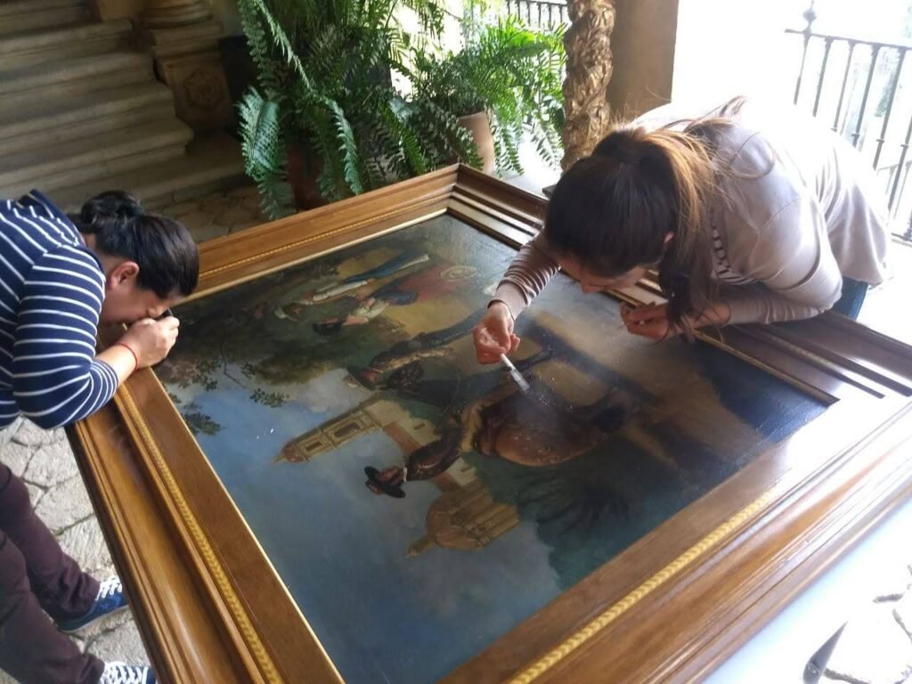 Dos mujeres haciendo una intervención en una obra pictórica.