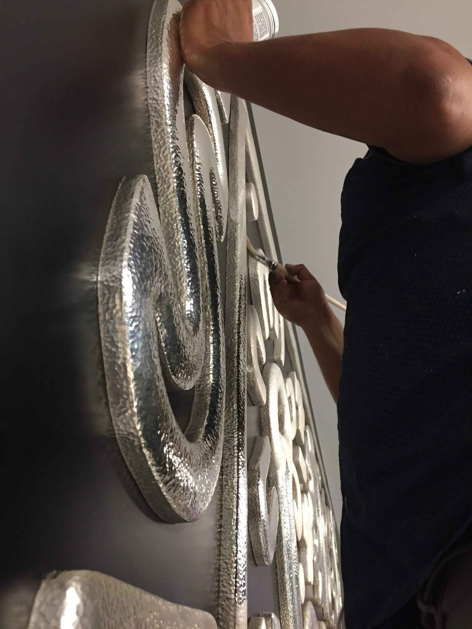 Persona limpiando un mural de plata.