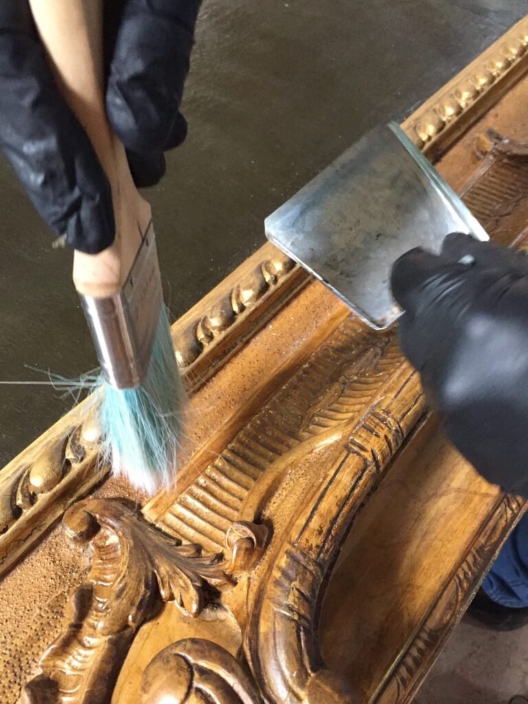 Manos limpiando mecánicamente el marco de un cuadro.