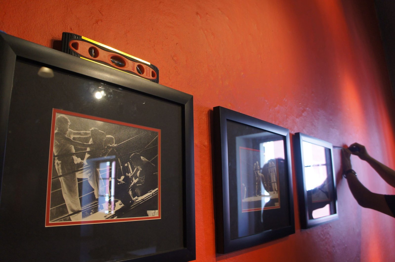 Cuadros colgados en una pared roja con un nivel.